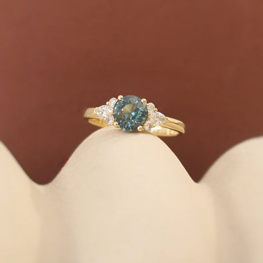 bague ornée d'un saphir teal épaulé de diamants-monture en or jaune